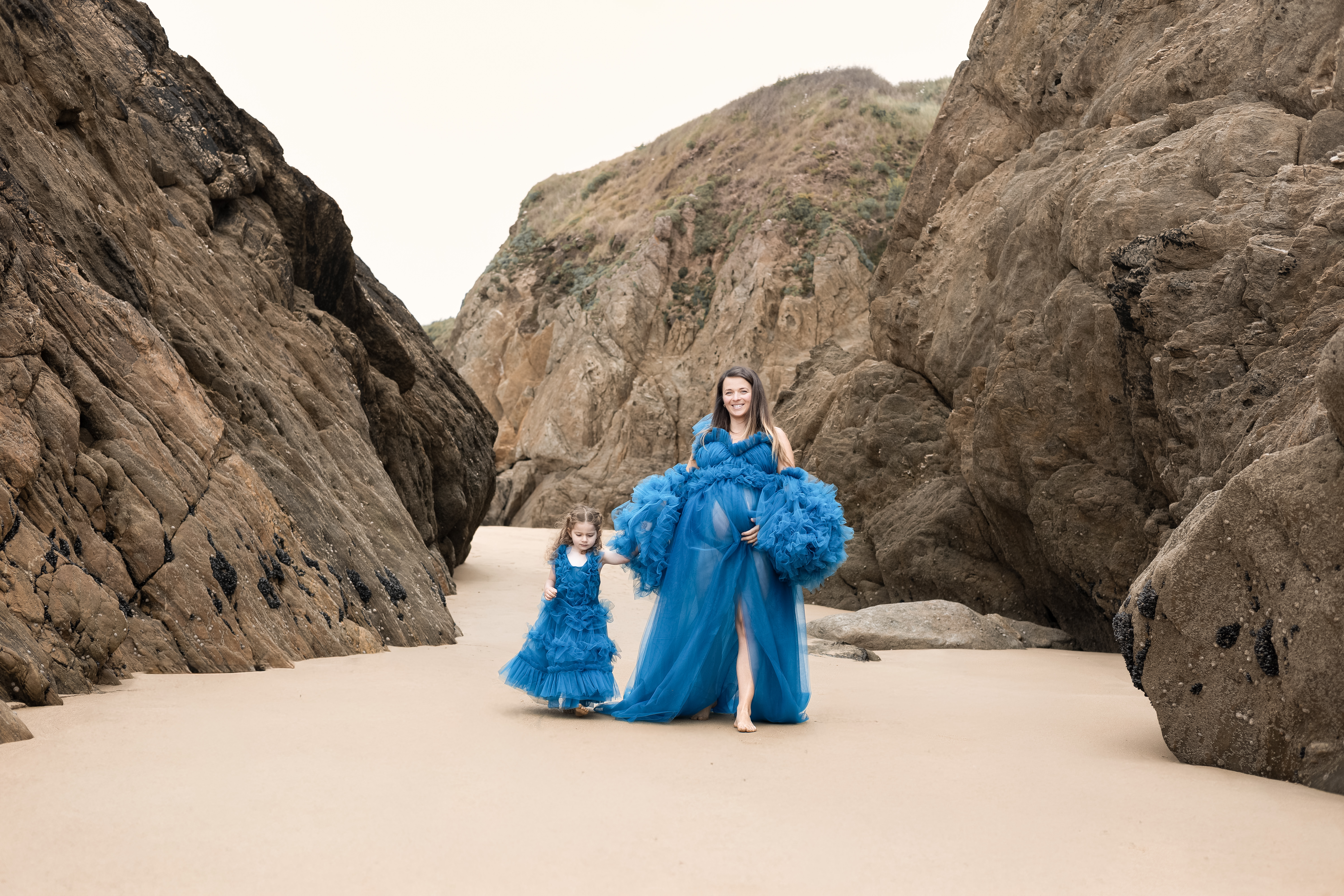 Mère et petite fille en robes bleues au milieu d’un passage entre les rochers