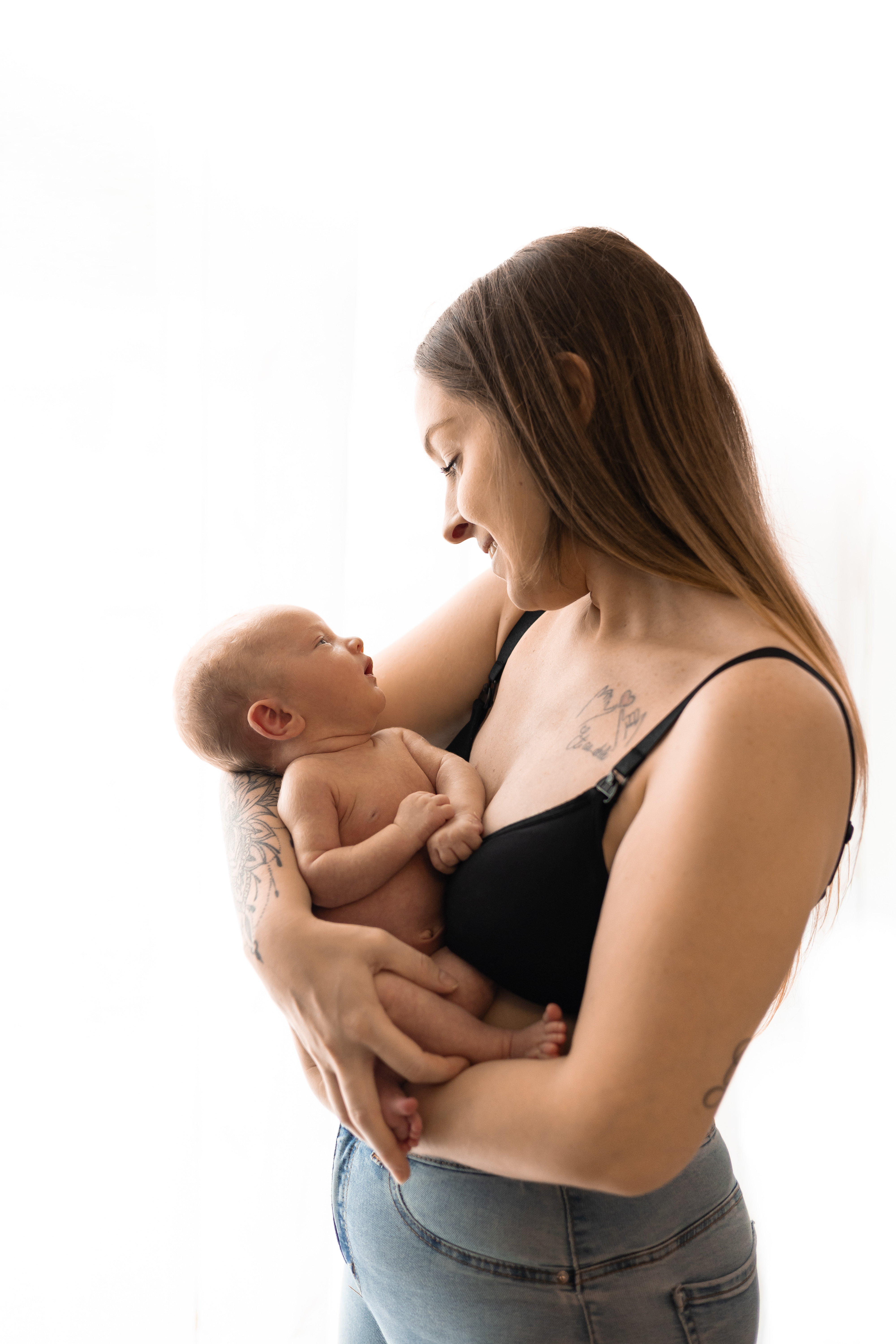 Mère souriante regardant son bébé endormi dans ses bras