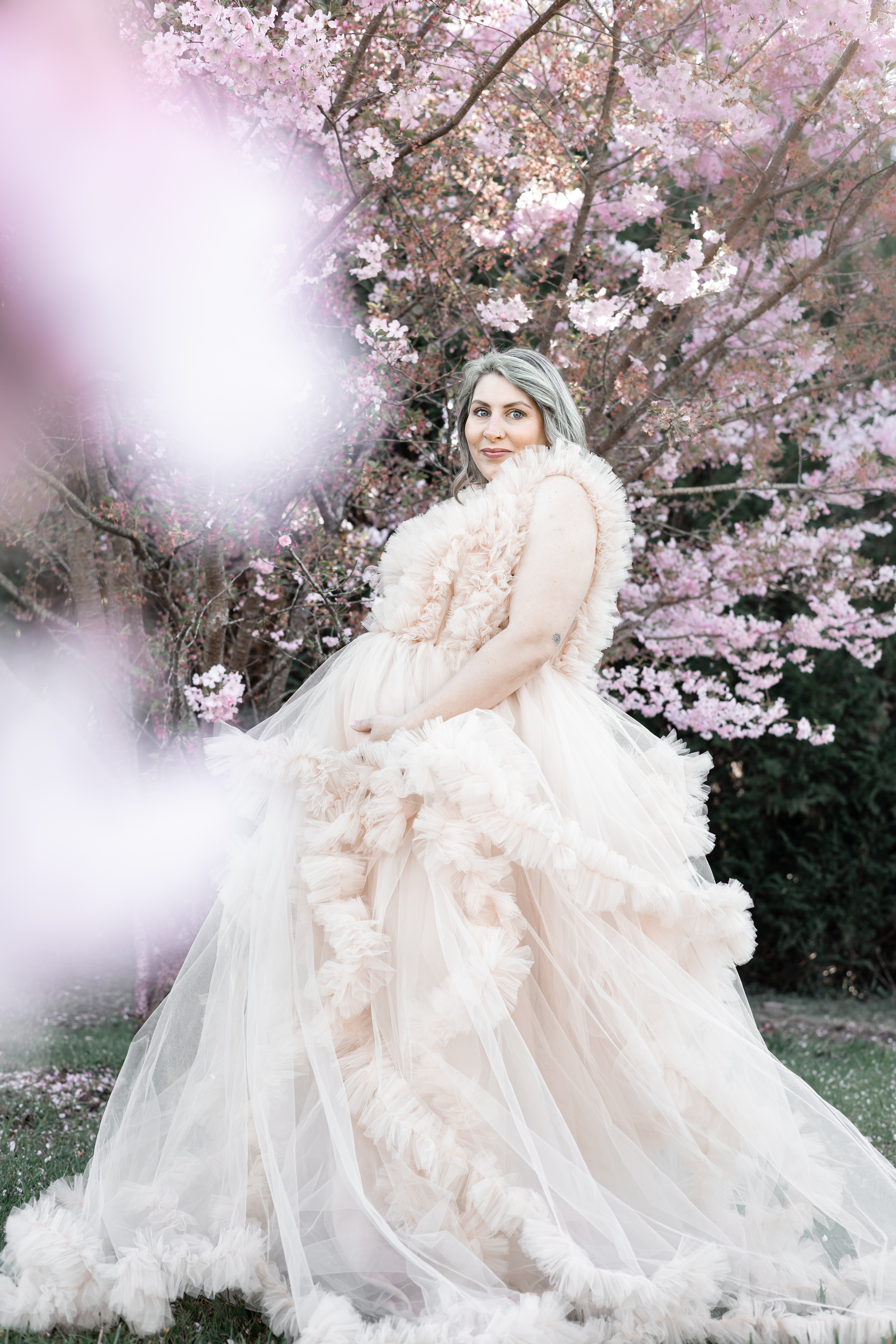 Future maman en robe ivoire vaporeuse sous les cerisiers roses