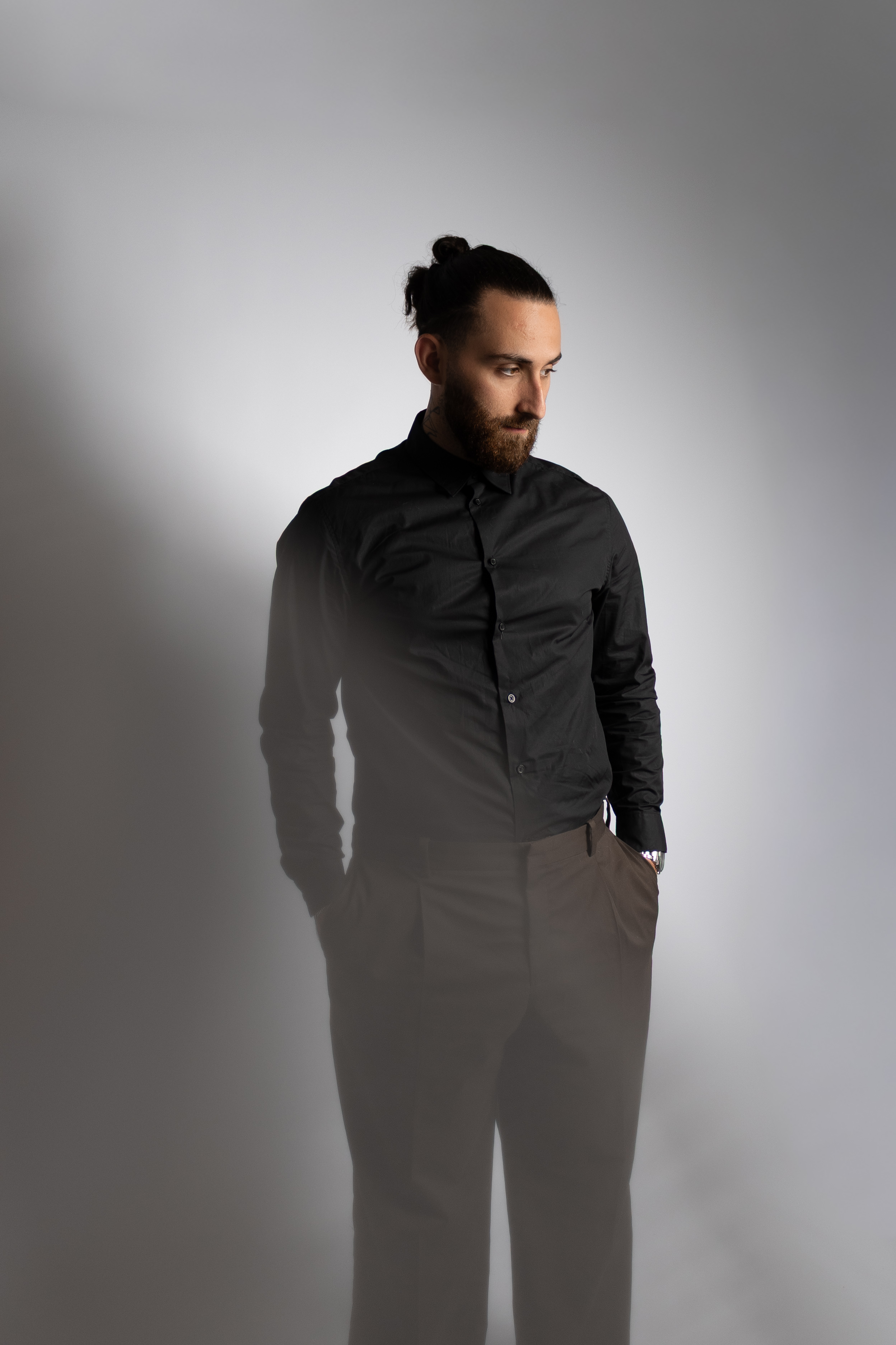 Homme en tenue sombre baissant le regard dans une lumière douce