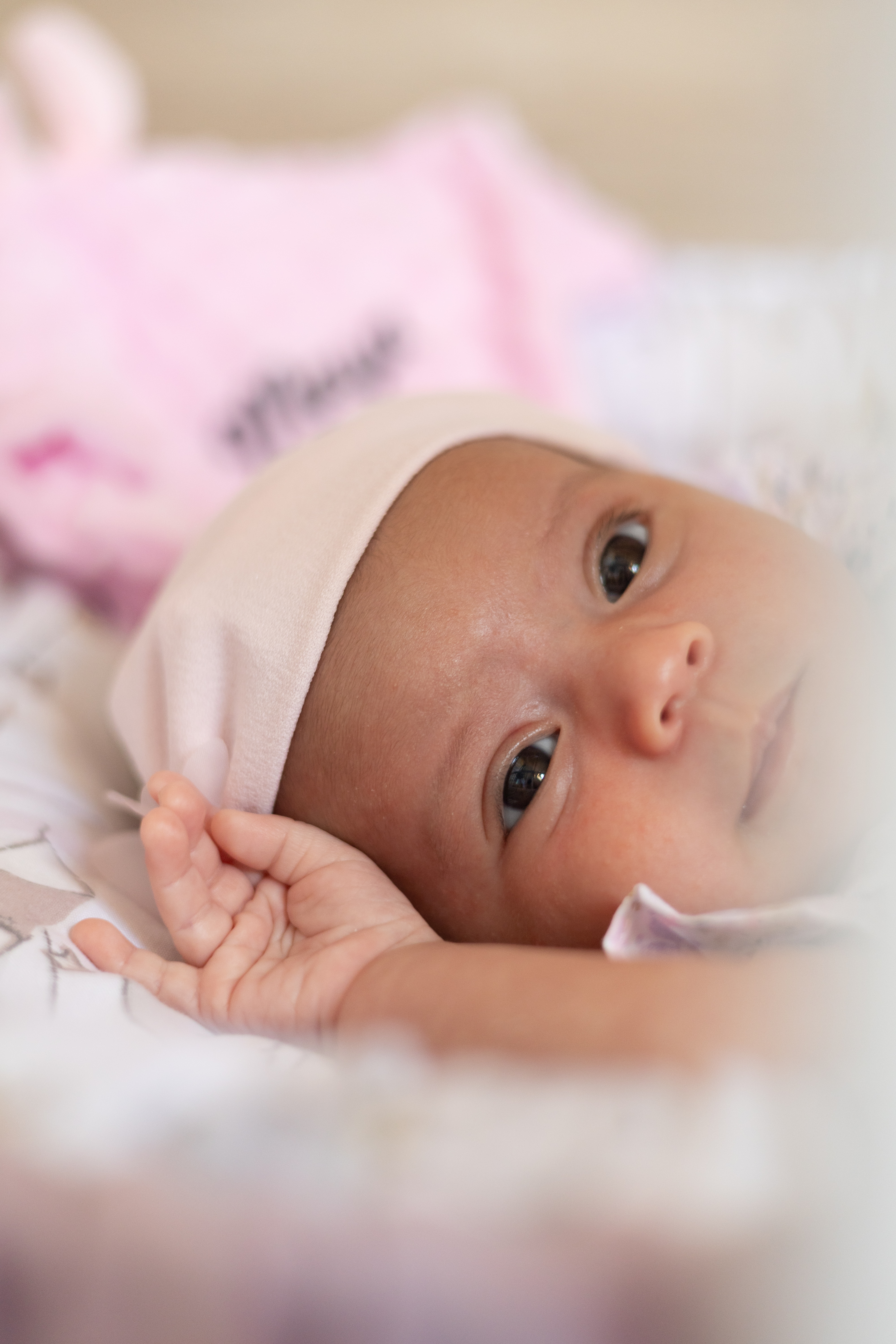 Portrait rapproché d’un nouveau-né éveillé portant un bonnet rose