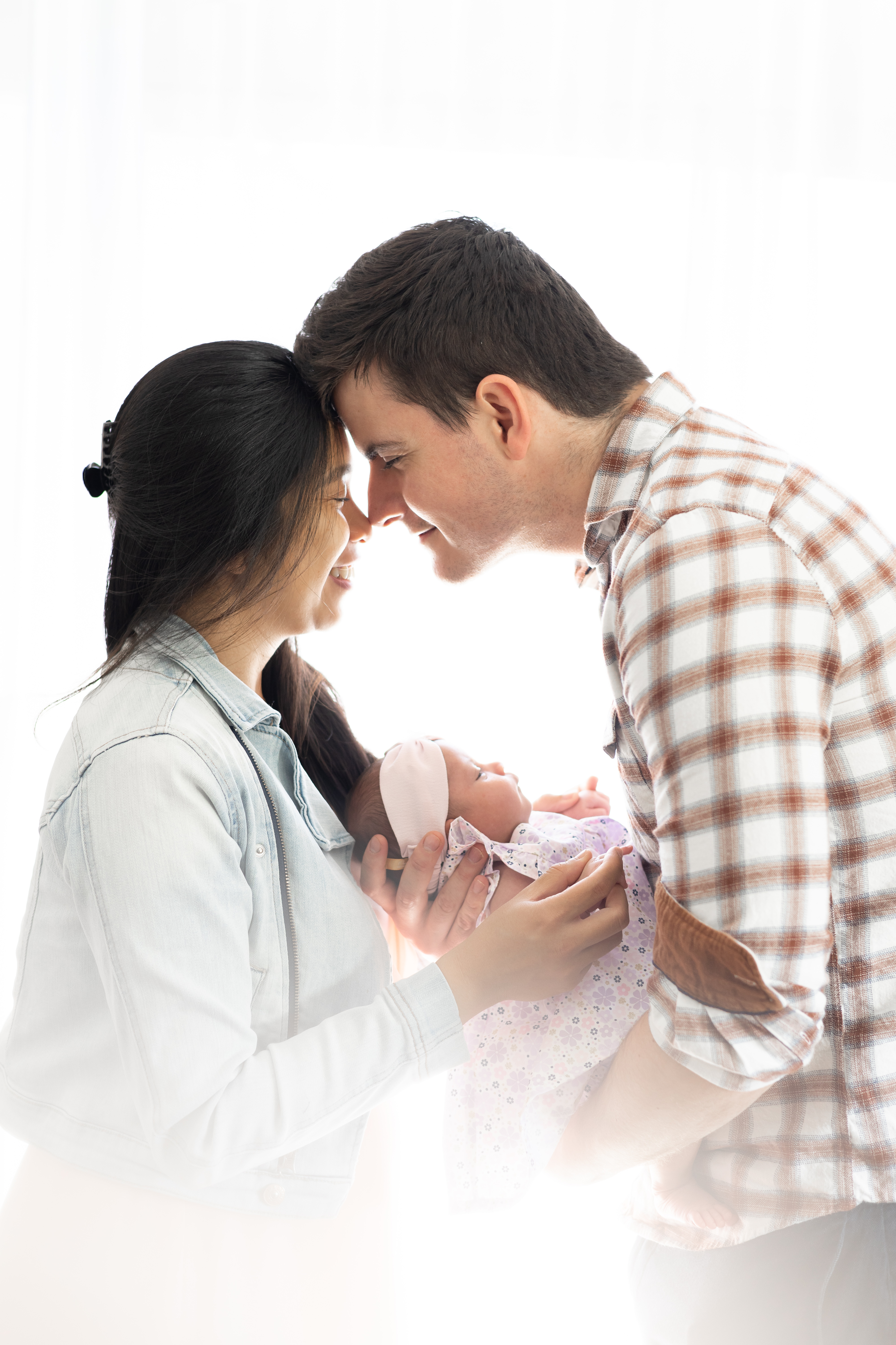 Parents s’embrassant au-dessus de leur bébé emmailloté