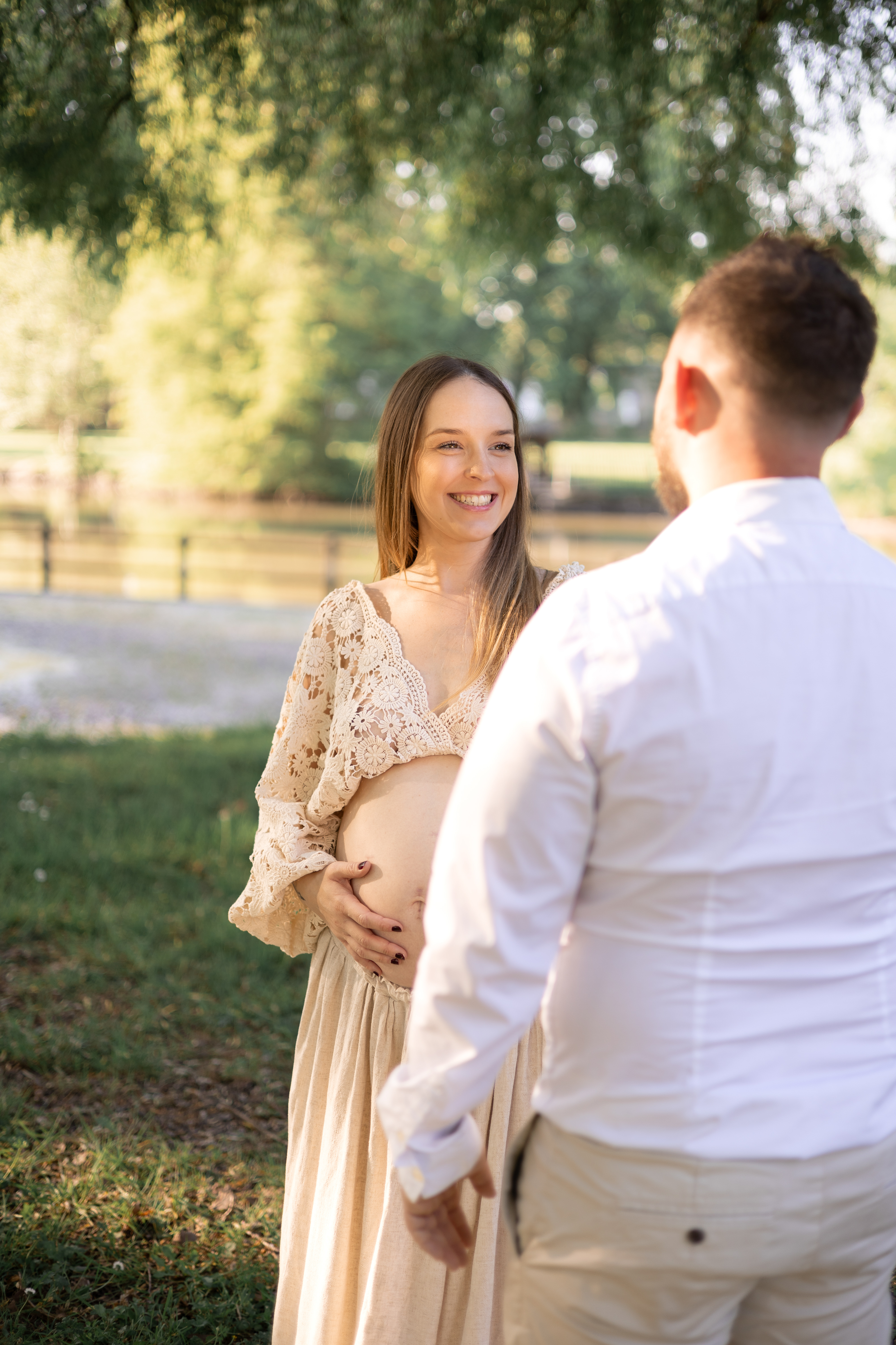 Futurs parents se souriant face à face dans un parc ensoleillé