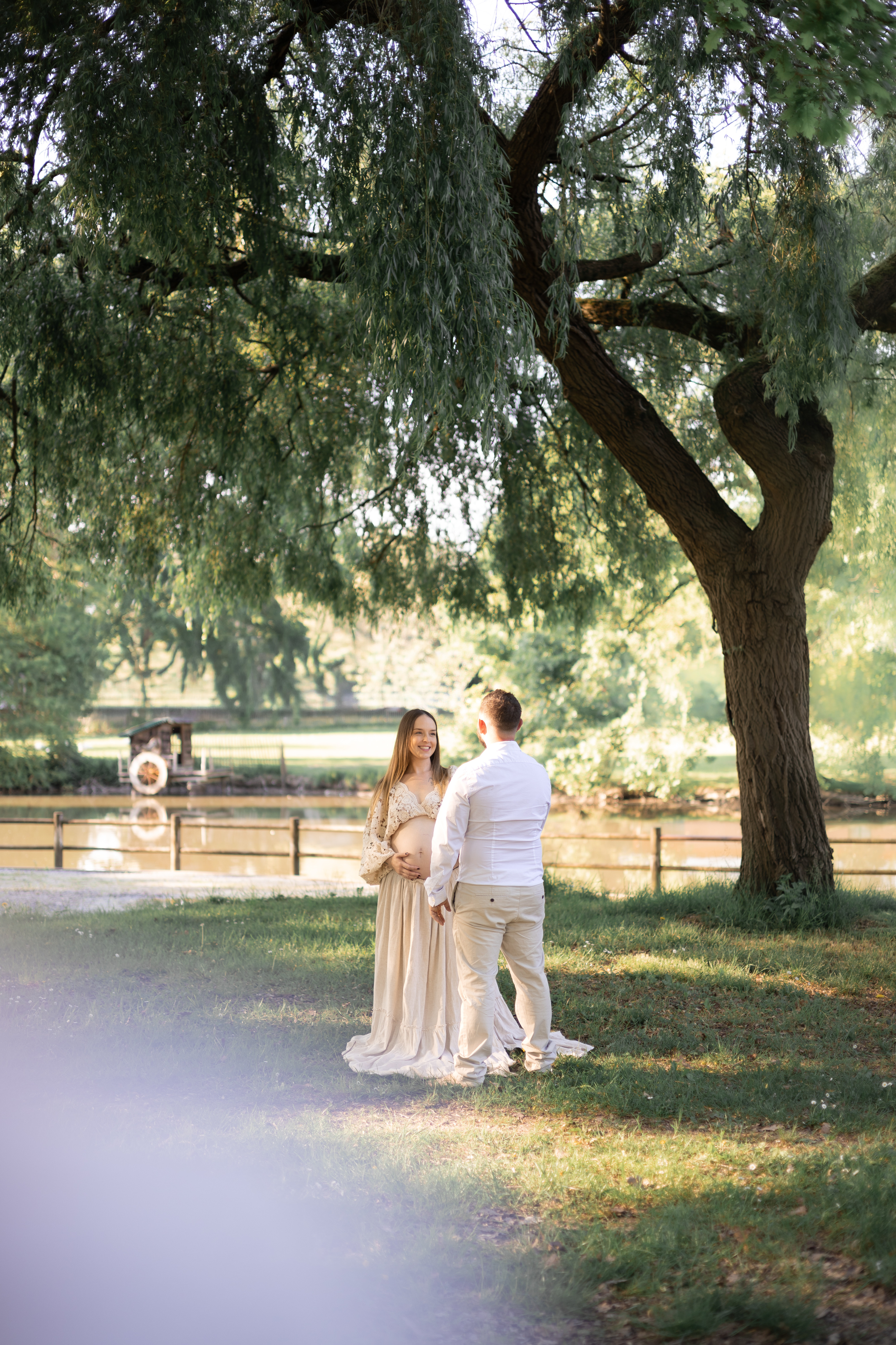 Couple attendant un enfant photographié au loin sous un grand arbre
