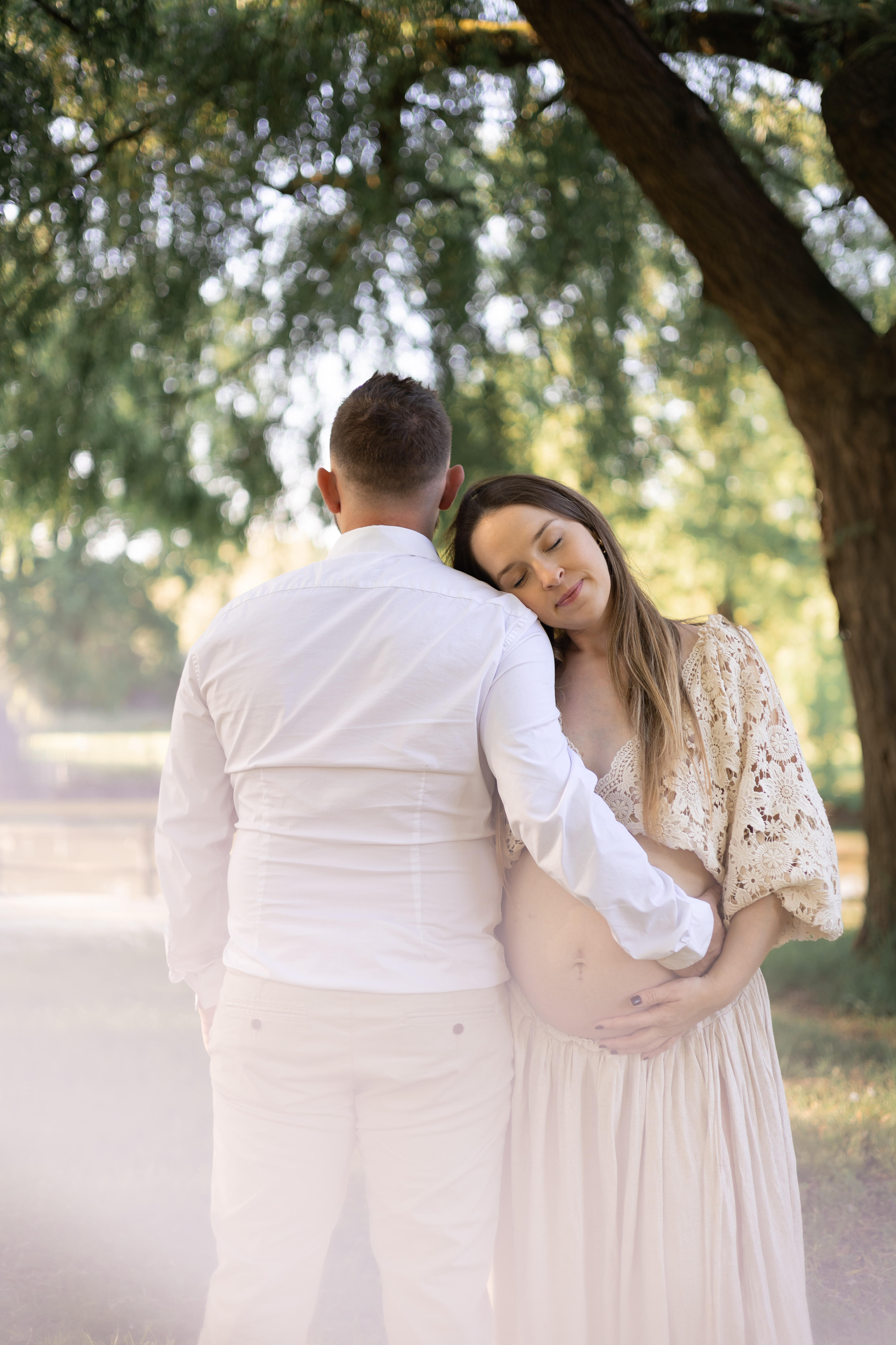 Futur papa entourant sa compagne enceinte et posant les mains sur son ventre