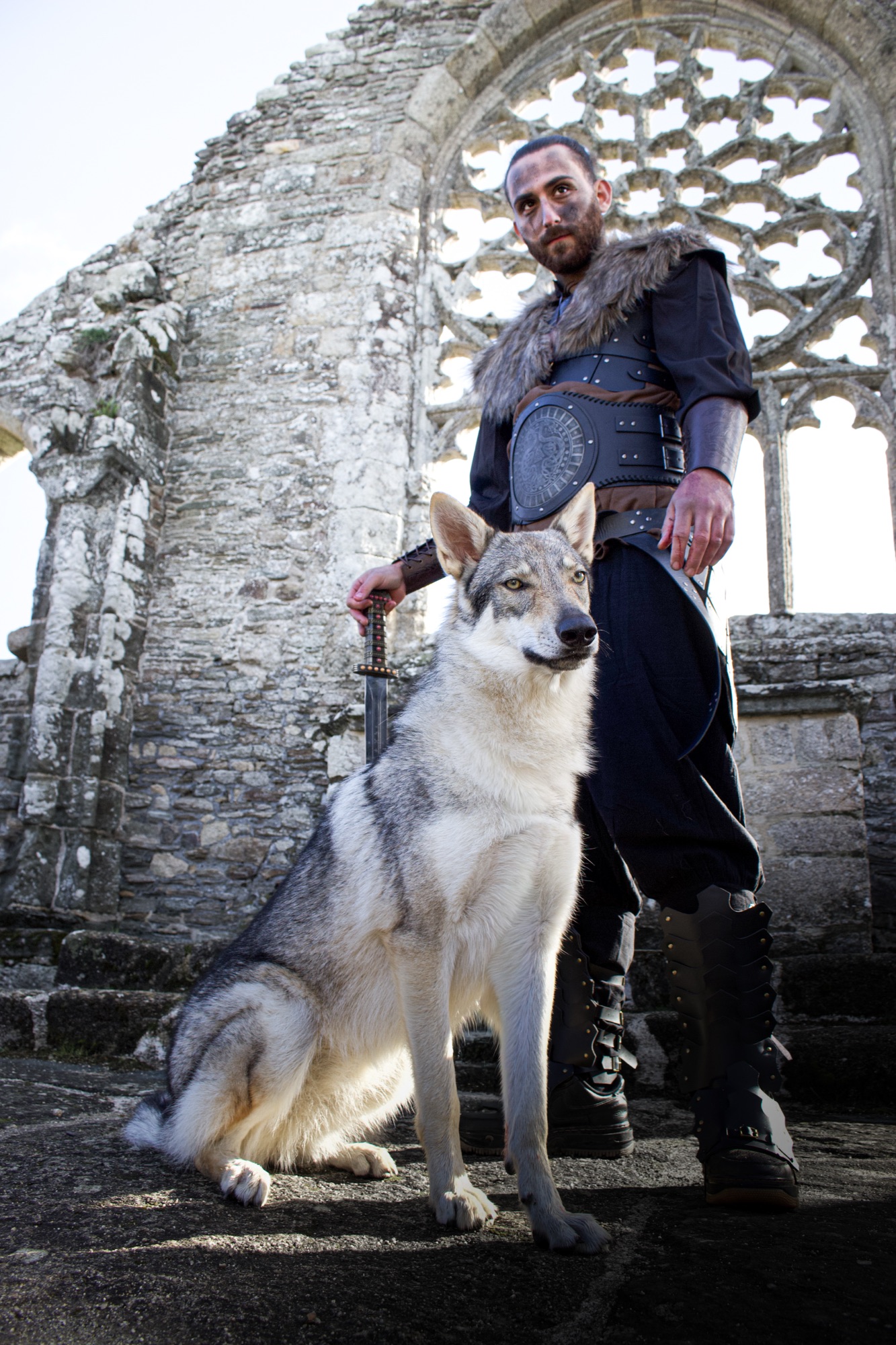 Guerrier viking debout avec un loup gris devant la rosace d’une abbaye