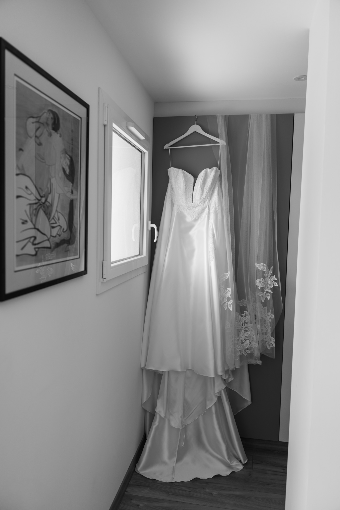 Robe de mariée et voile suspendus près d’une fenêtre avant la cérémonie