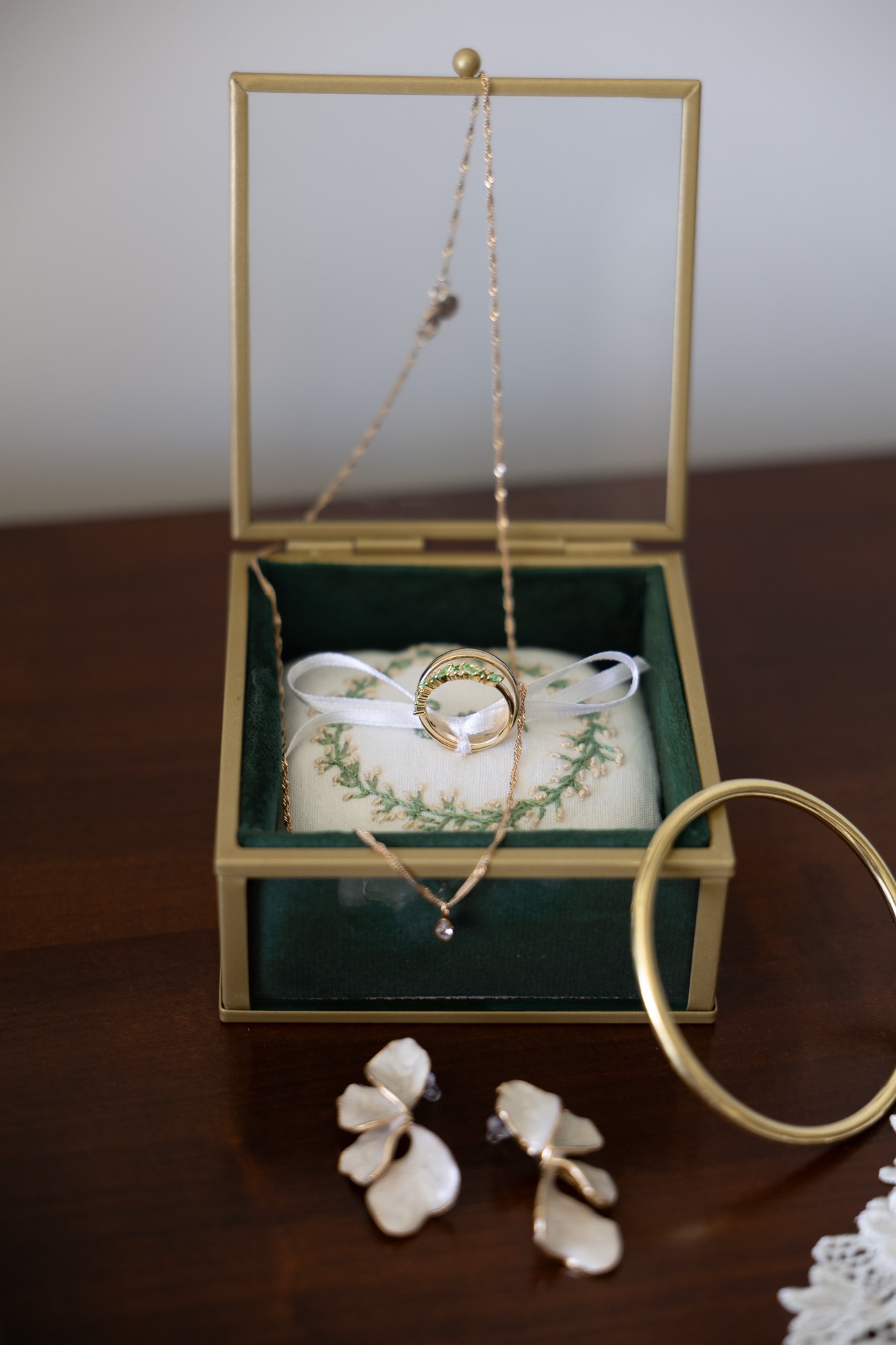 Alliances et bijoux de mariage présentés dans un écrin vert